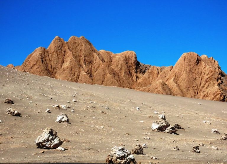 Layers of weathered rock and distant volcanoes create the dramatic scenery inside Valle de la Luna. Exploring by car makes it easy to stop at viewpoints throughout the park.