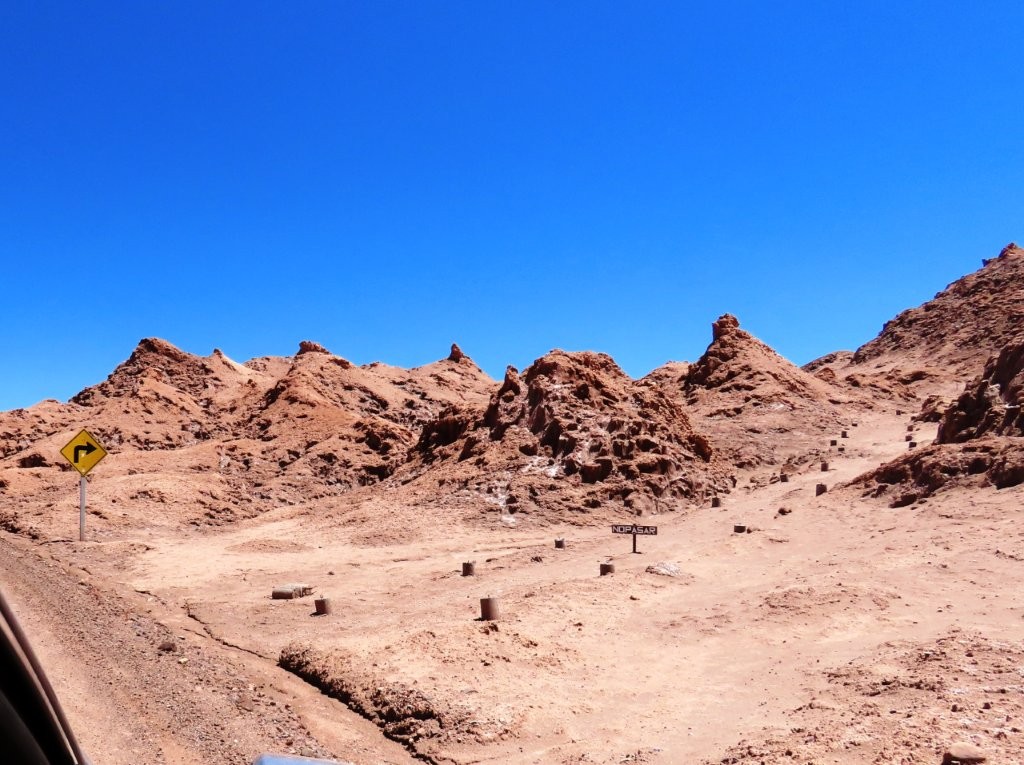 Salt-covered ridges and sculpted rock formations create an almost lunar landscape beneath a brilliant blue sky.
