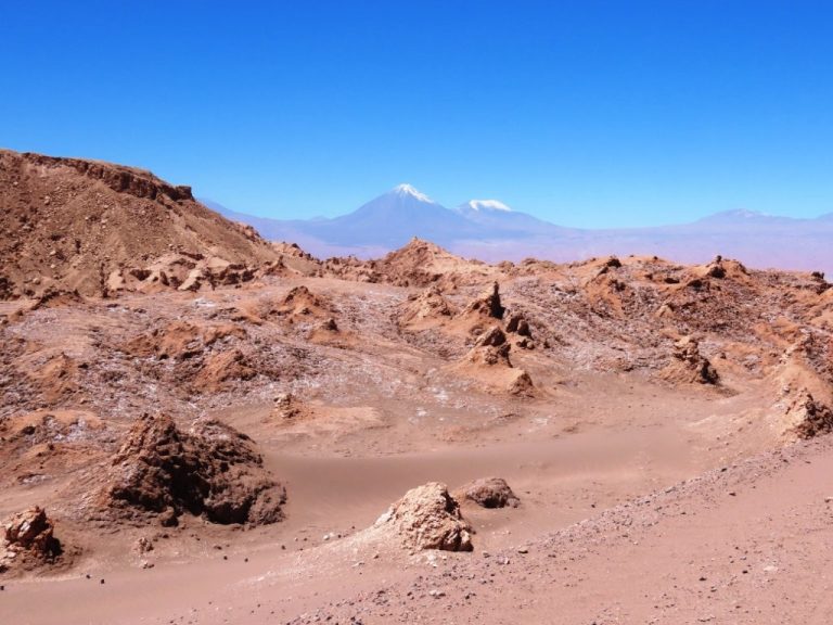 Panoramic view of the rugged rock formations and winding road through Valle de la Luna in Chile's Atacama Desert. This landscape introduces one of the region's most popular self-drive adventures.