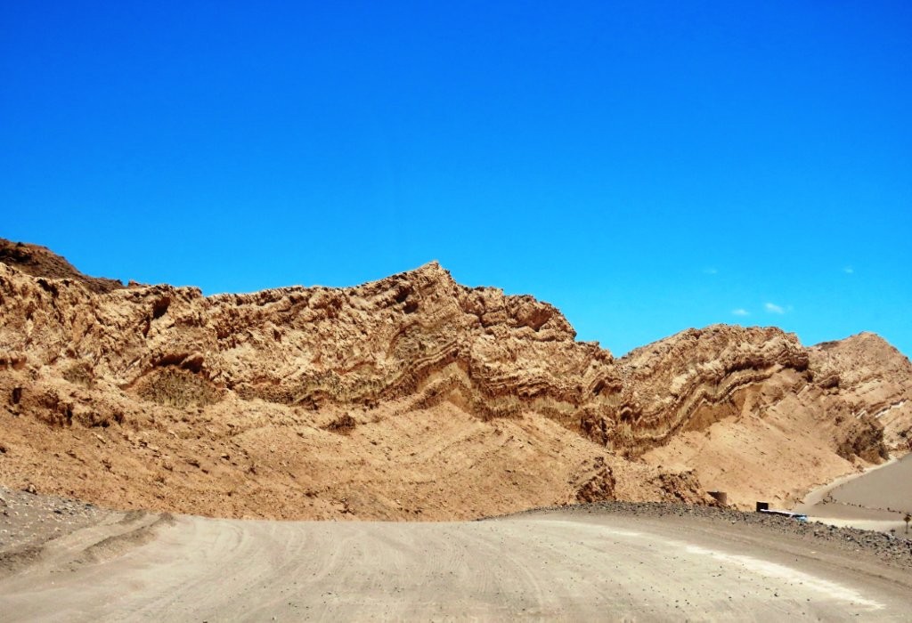 A quiet desert road winds between towering rock formations inside Valle de la Luna. The landscape feels surprisingly empty and peaceful.