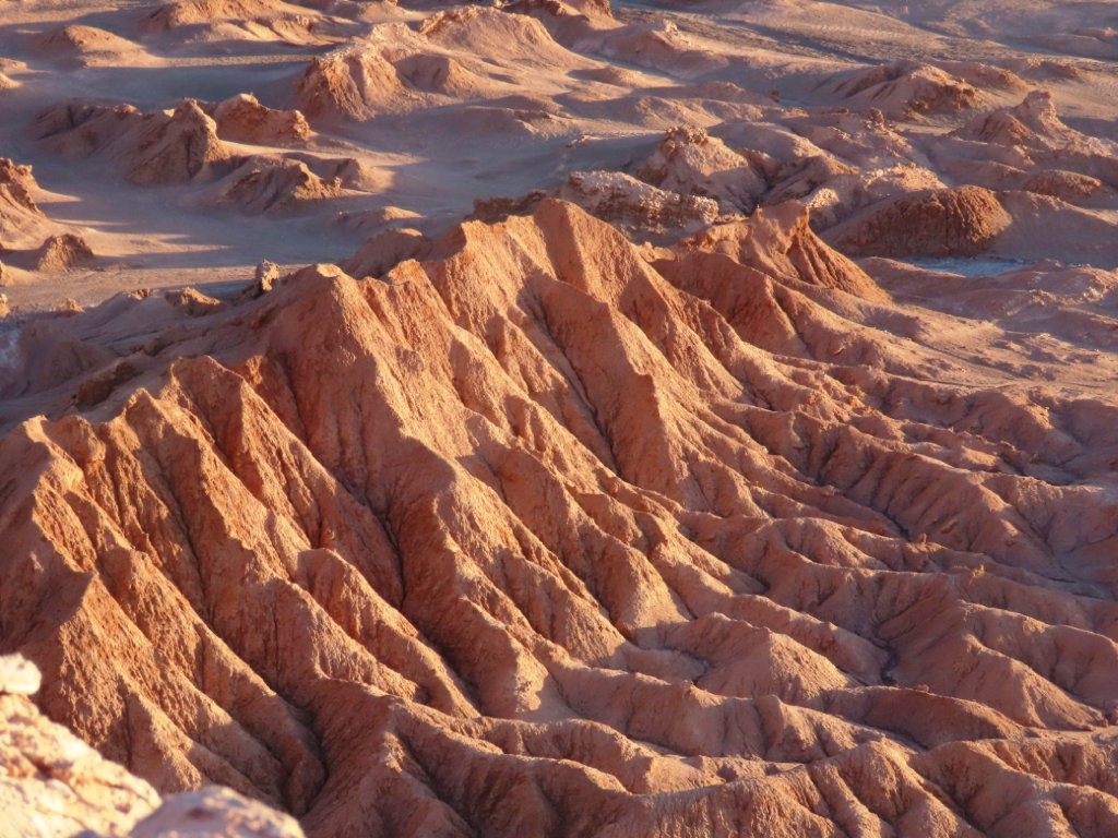 Late afternoon light begins to illuminate the cliffs and valleys viewed from Ckari Mirador near San Pedro de Atacama. Many visitors gather here to watch the desert sunset.