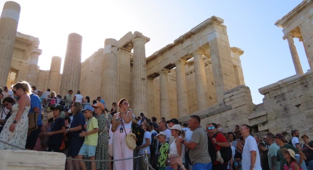 A dense crowd of visitors gathers beneath the towering ancient columns at the entrance to the Acropolis in Athens. The busy tourist setting shows exactly the type of crowded area where Kari’s guide warned the group to be especially alert for pickpockets.