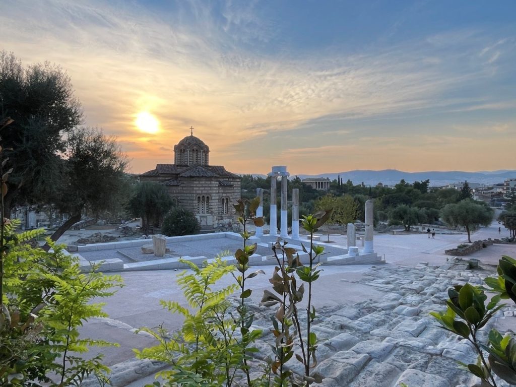 Ancient stone ruins stretch across the Agora with trees and the Temple of Hephaestus visible in the distance beneath the evening sky. Our walking tour gave us a look at important archaeological sites without requiring a separate visit to each one.