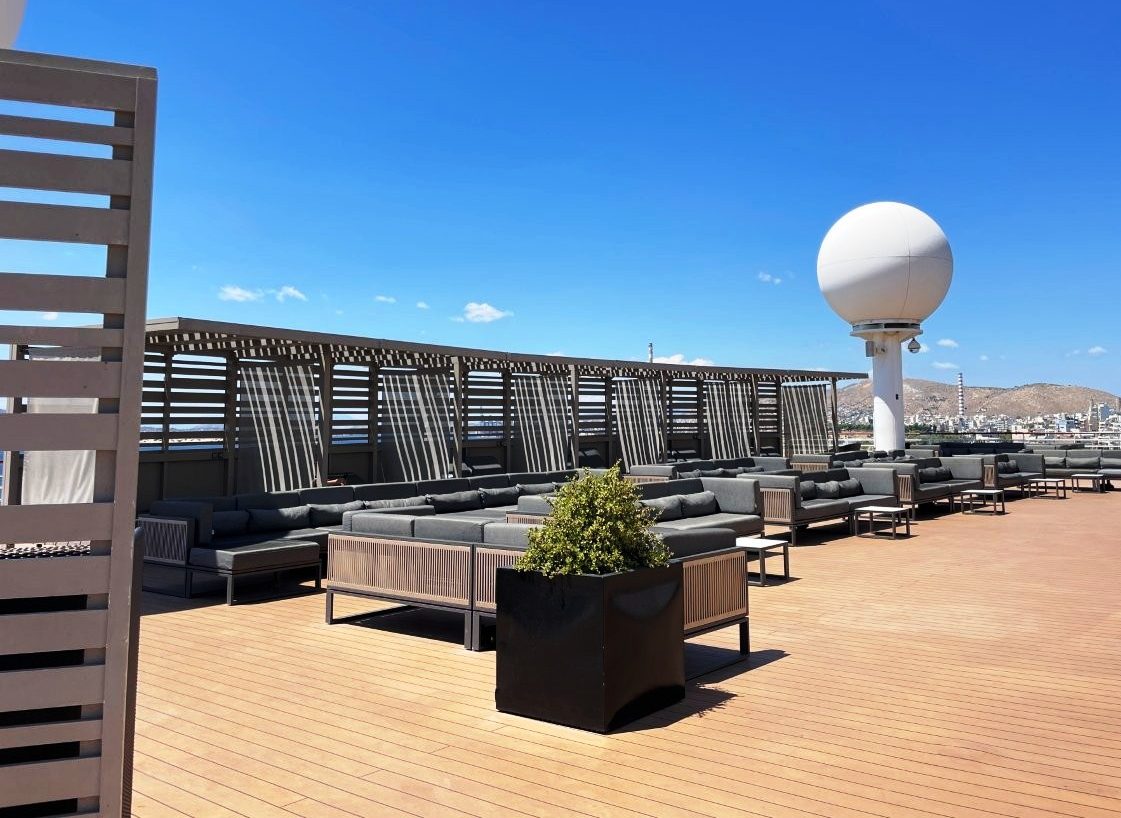 An open rooftop deck aboard Celebrity Infinity has lounge seating, wood-toned flooring and wide stretches of blue sky overhead. Quiet outdoor spaces like this helped the ship feel comfortable rather than crowded during much of the cruise.