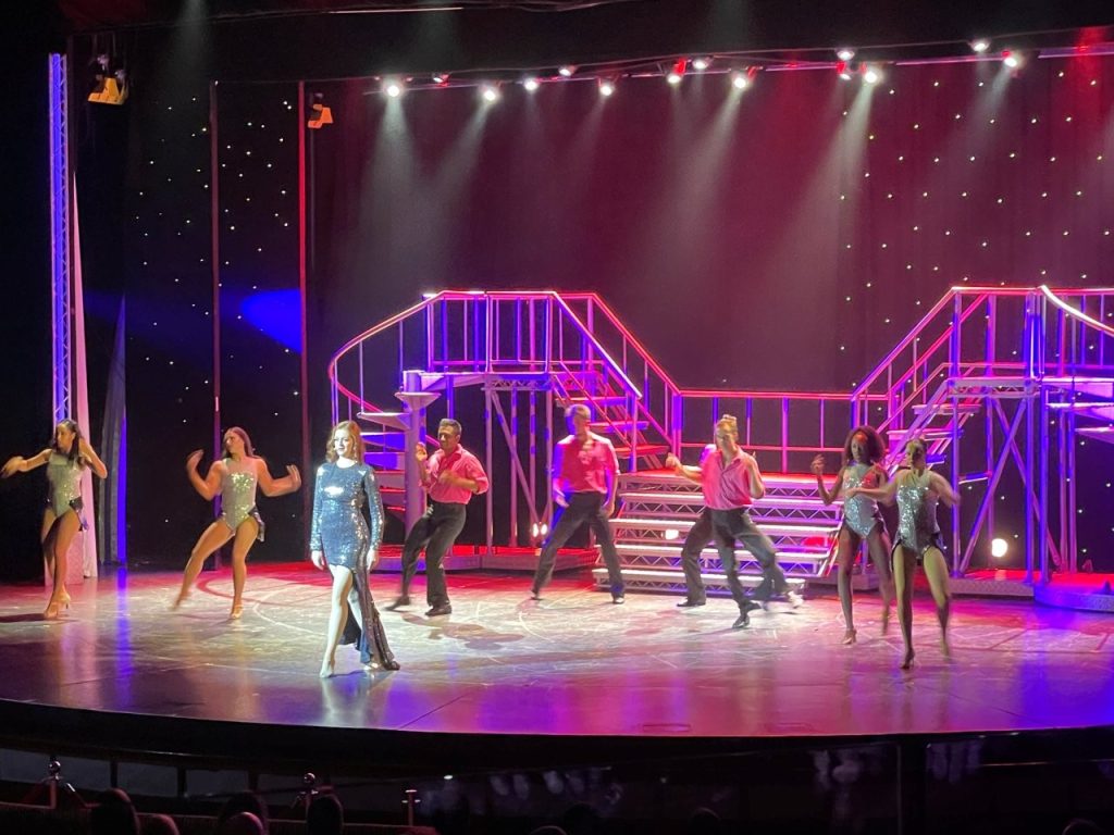 Performers take the stage beneath colorful theatrical lighting during an evening show aboard Celebrity Infinity. Production shows, aerial performers, comedy and live music made the entertainment one of our favorite surprises.
