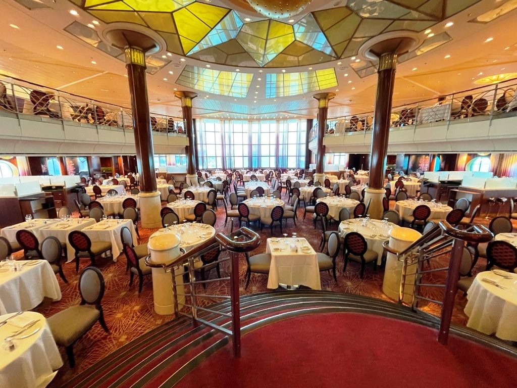 Rows of white-tablecloth tables fill the elegant two-level Trellis Restaurant aboard Celebrity Infinity, with tall windows stretching across the far wall. Kari and Bill enjoyed dining here without buying drink packages, showing that paying à la carte can work just as well when it fits normal habits.