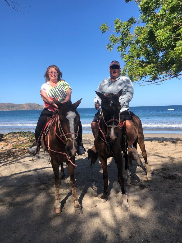 Kari & Bill ride horses on the beach in Costa Rica.